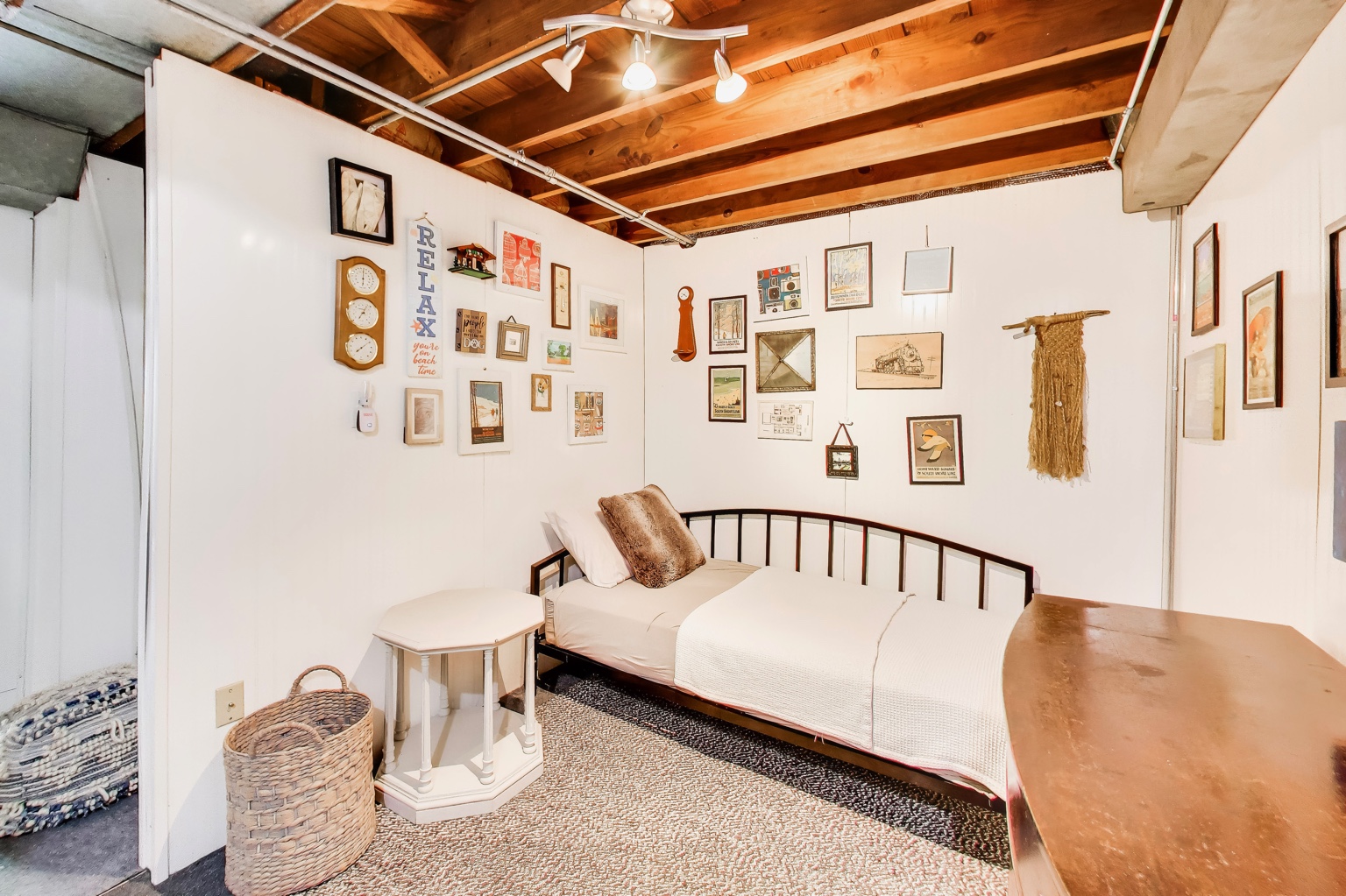 Additional sleeping area in the lower-level recreation room with a daybed and exposed wood ceiling