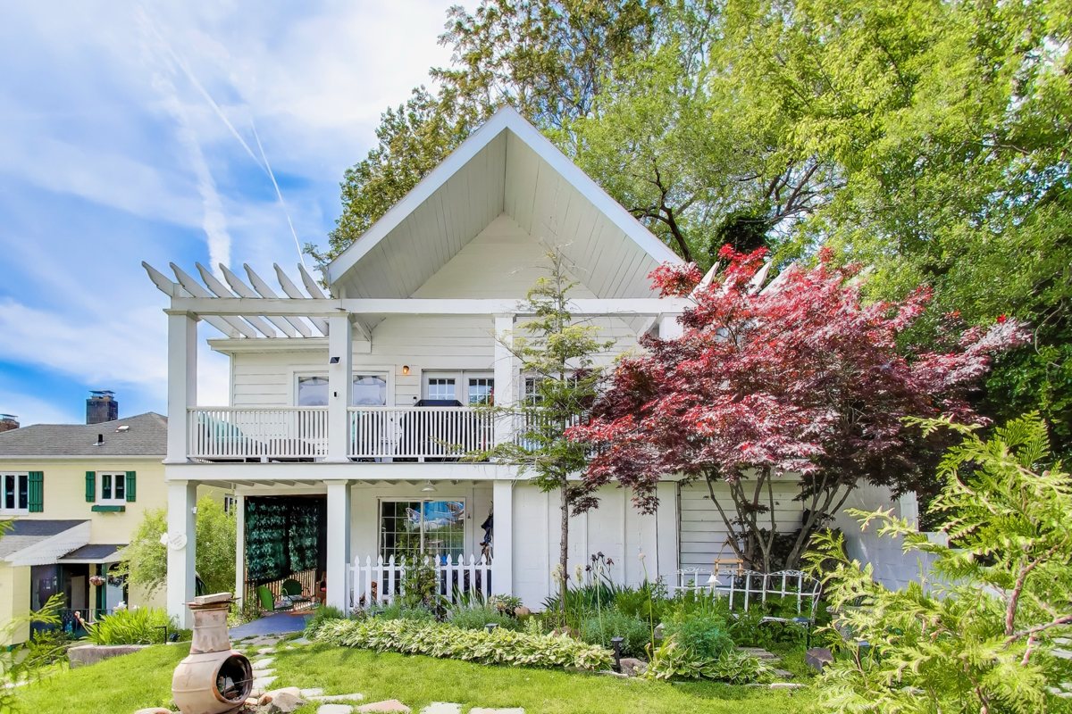 Front of Emmet’s Place, a white Miller Beach cottage with an upper balcony and garden