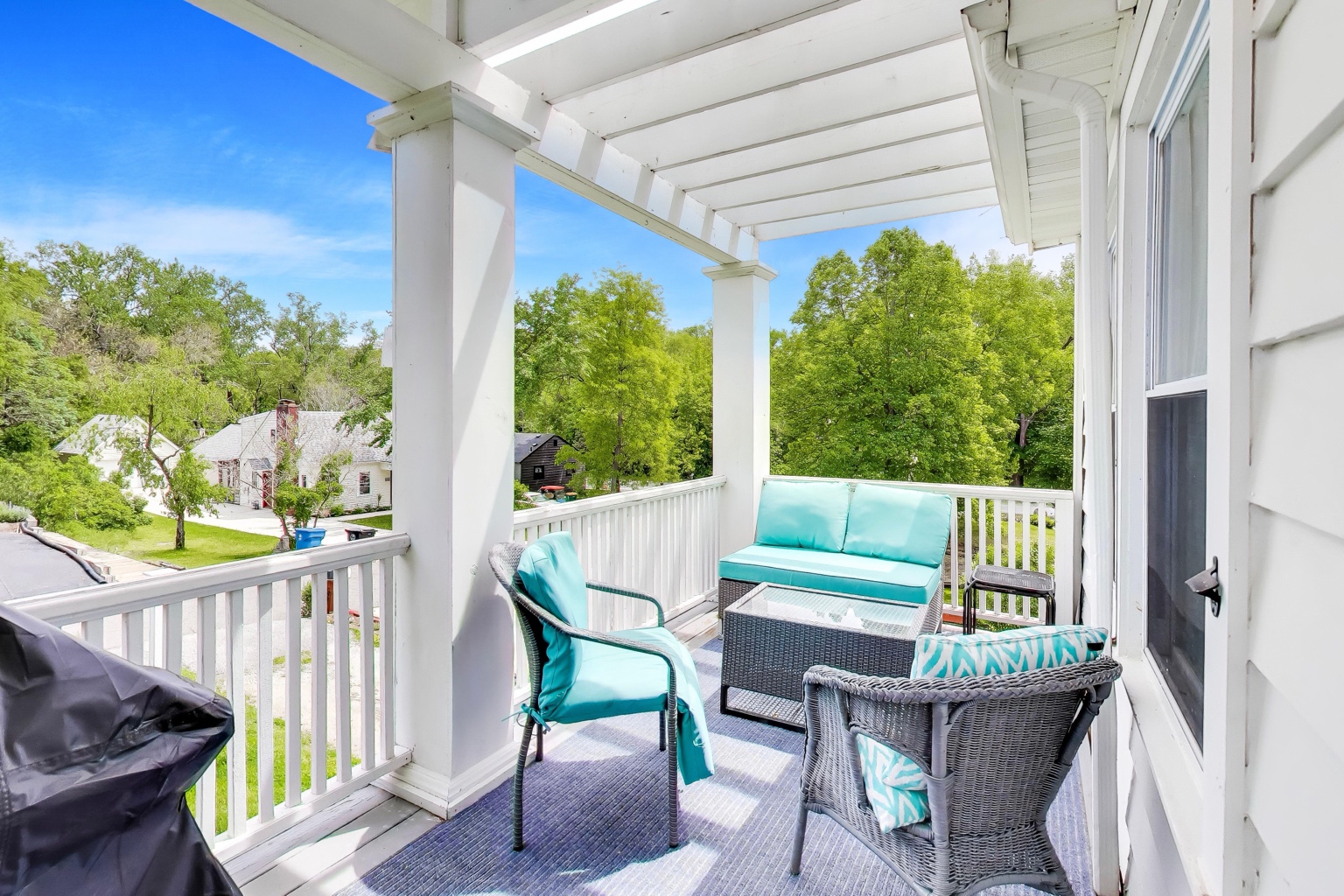 Covered upper patio with turquoise seating, a coffee table, and a grill